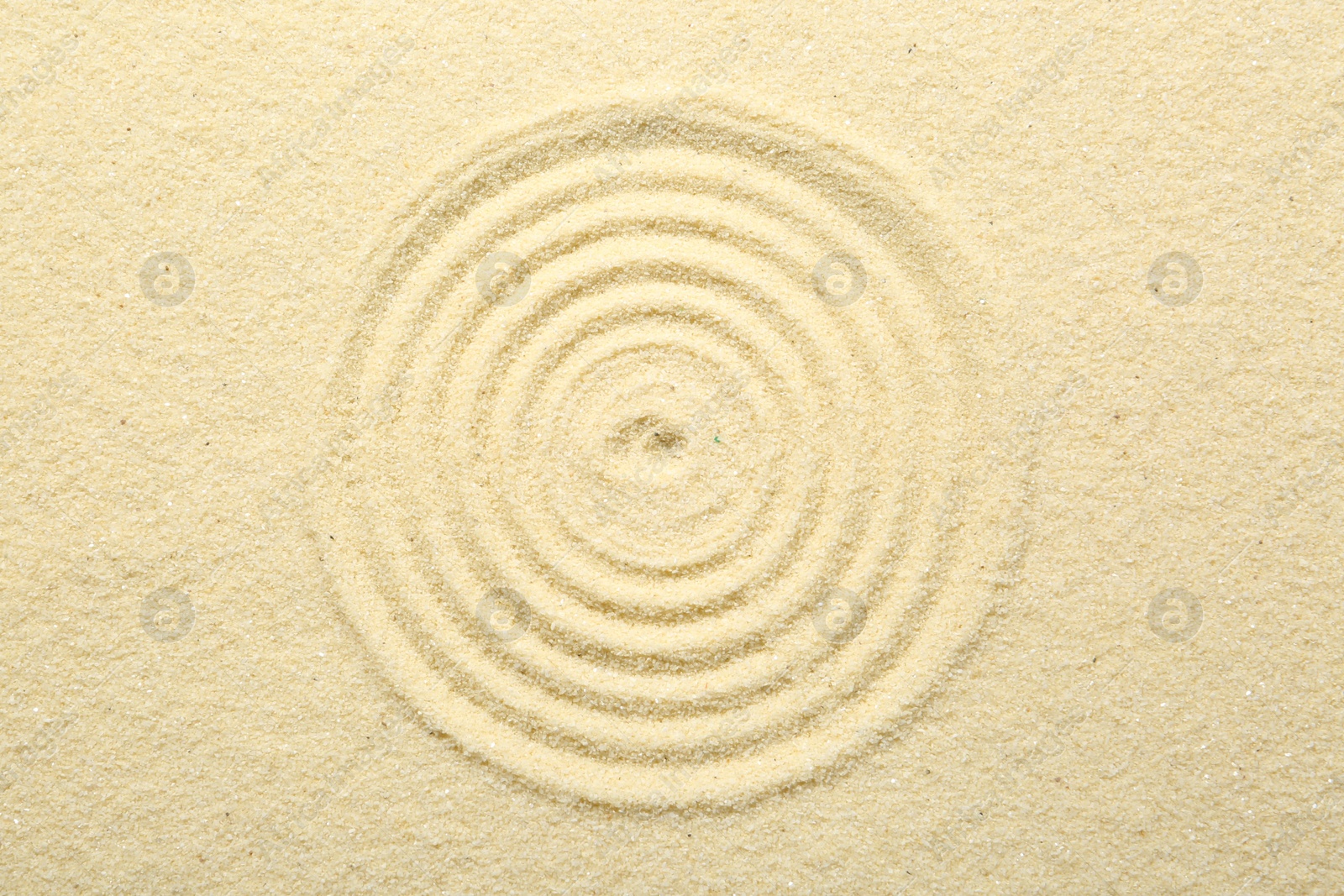 Photo of Zen rock garden. Circle pattern on beige sand, top view