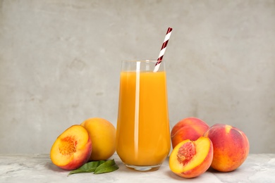 Photo of Natural peach juice and fresh fruits on grey table