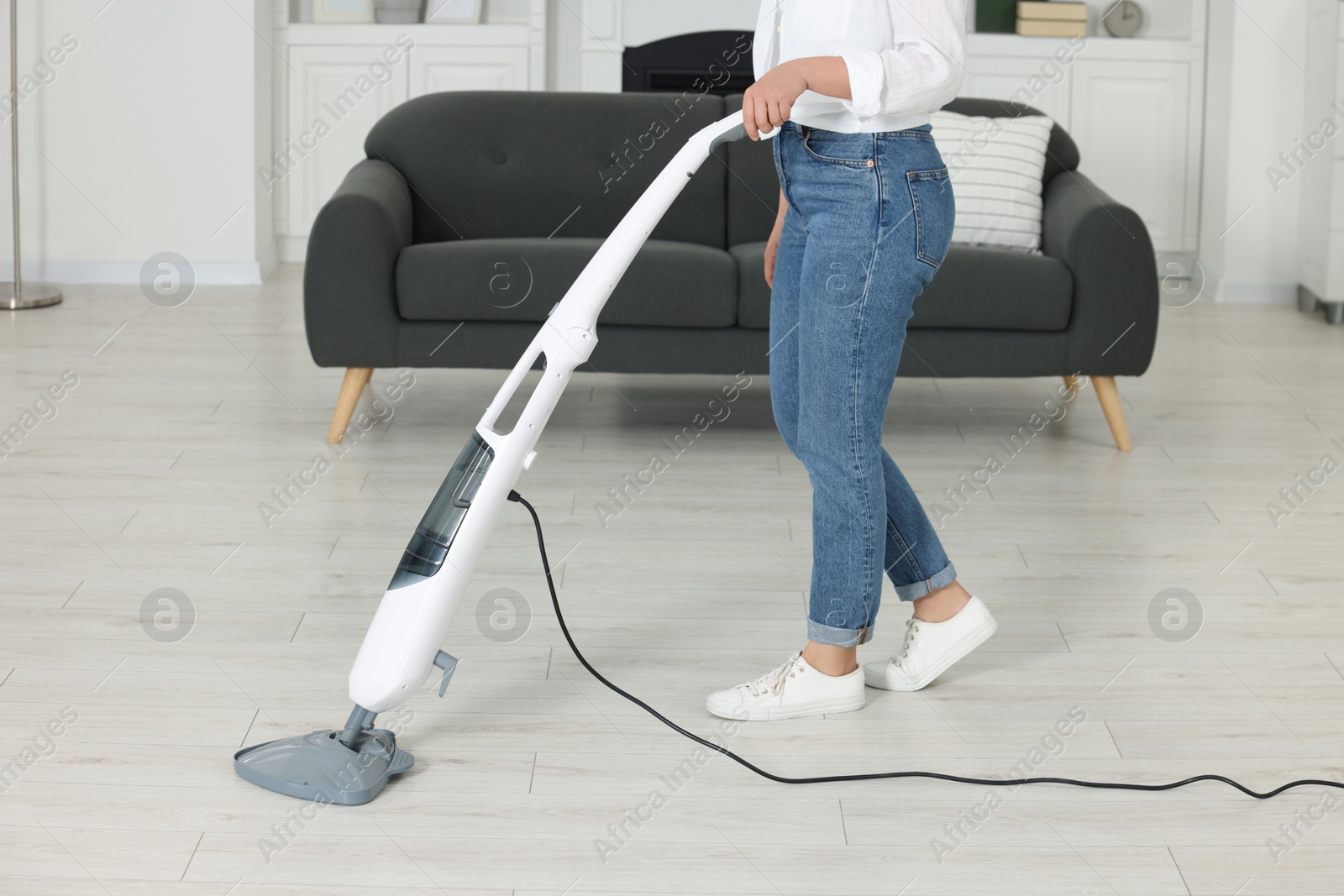 Photo of Woman cleaning floor with steam mop at home, closeup