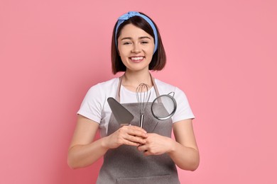 Happy confectioner with professional tools on pink background