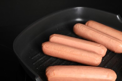 Photo of Cooking vegan sausages in grill pan on cooktop, closeup