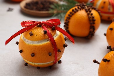 Pomander balls made of tangerines with cloves on grey table, closeup