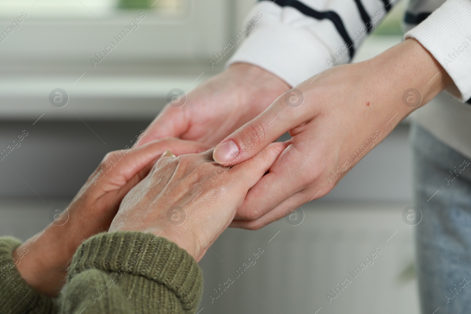 Photo of Caregiver helping elderly woman at home, closeup