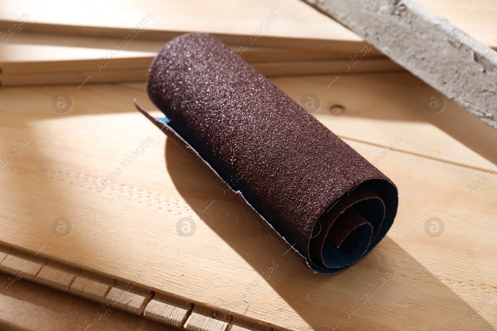 Photo of One rolled sheet of sandpaper on wooden planks