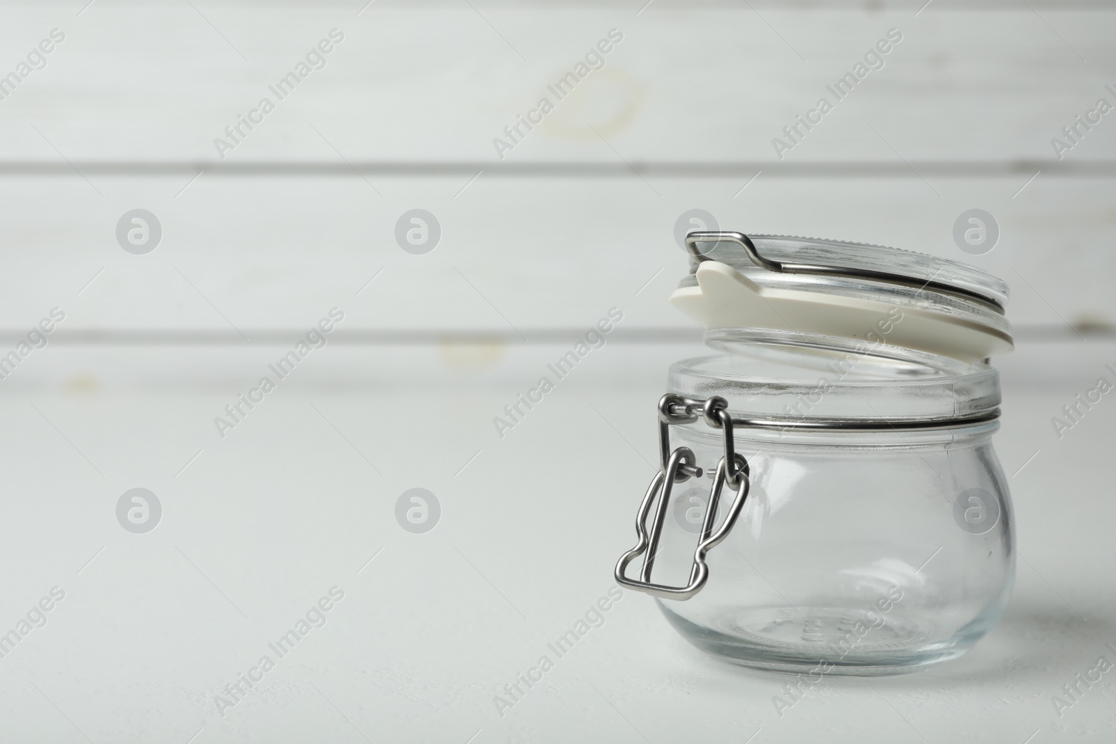 Photo of Empty glass jar on white table, space for text