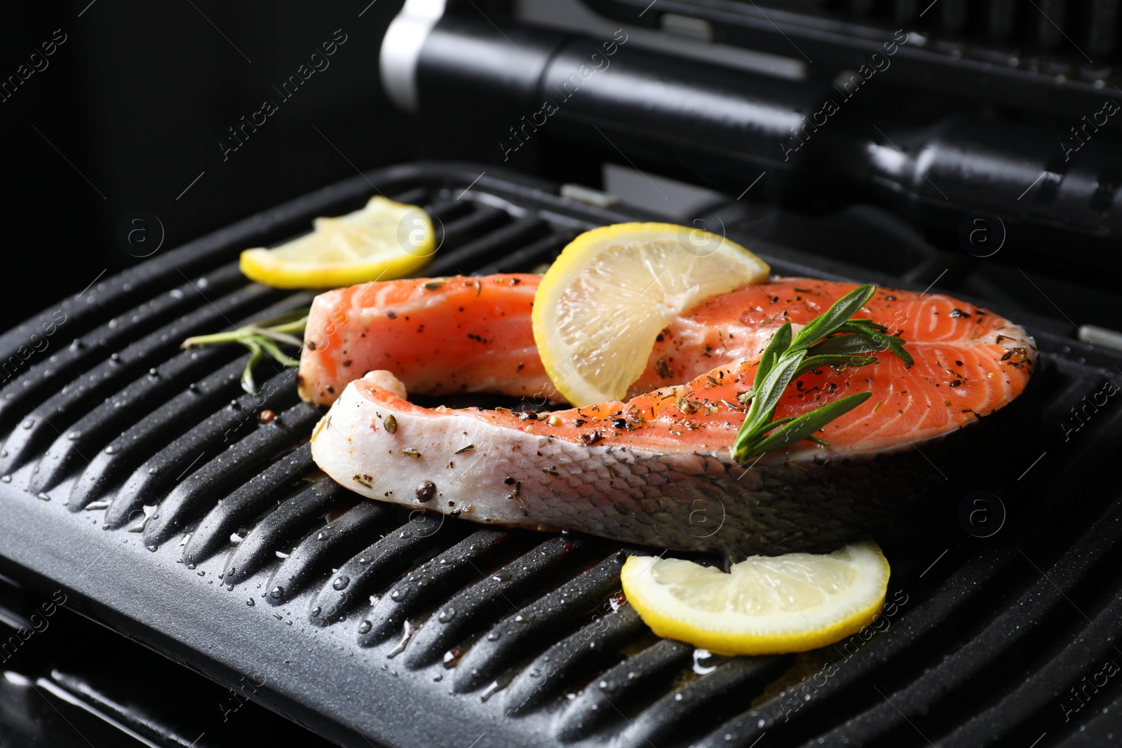 Photo of Cooking salmon. Grill with fresh fish steak, lemon and rosemary