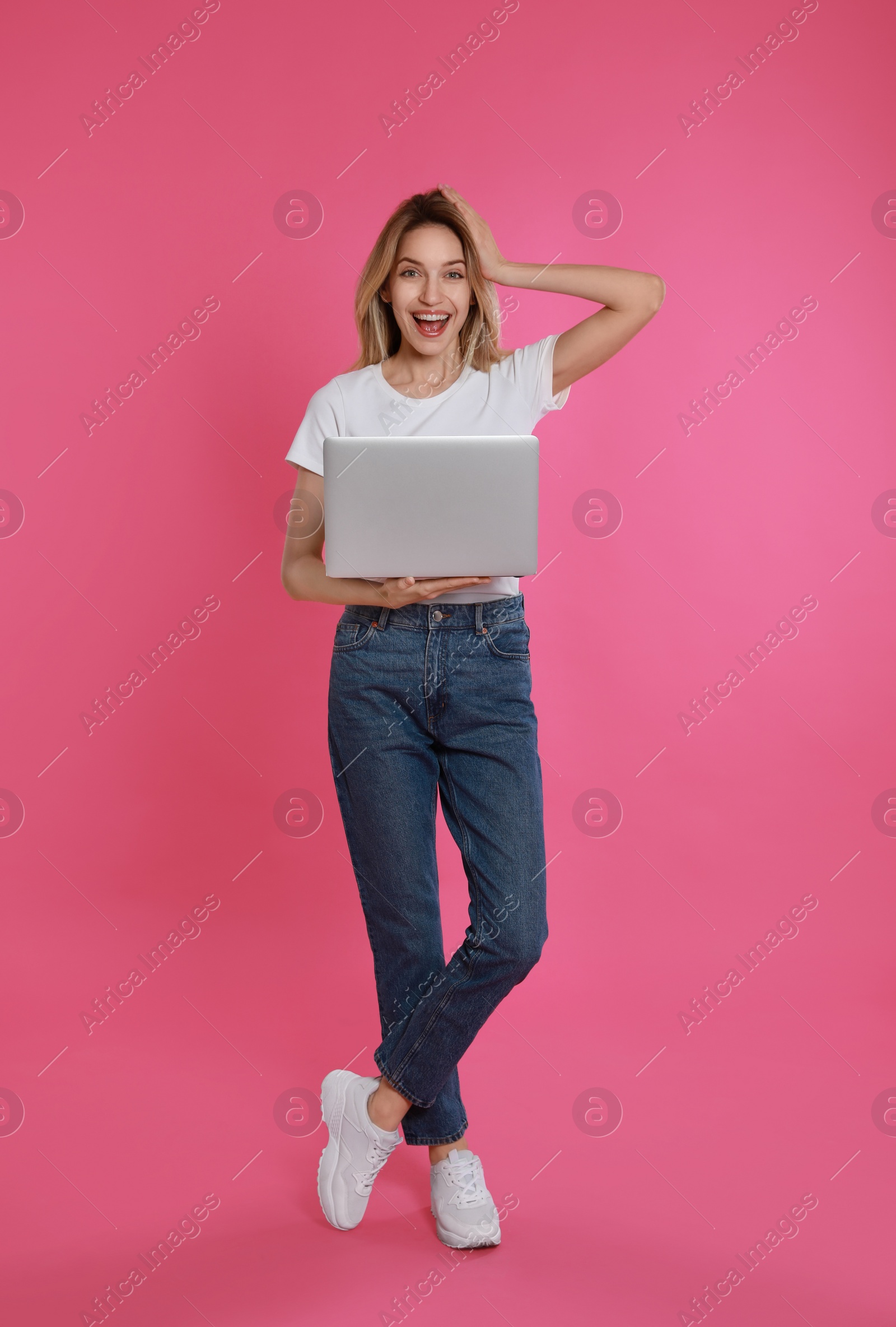 Photo of Young woman with modern laptop on pink background