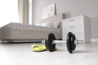 Steel dumbbell and ankle weights on floor indoors. Fitness at home