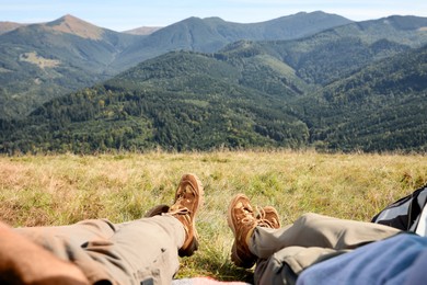 Photo of Couple lying on grass in mountains, closeup