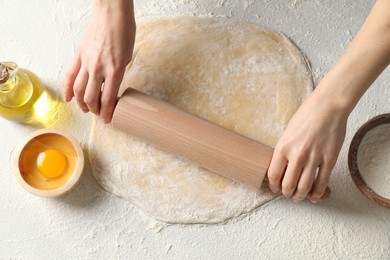 Photo of Woman rolling raw dough at table, closeup