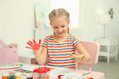 Cute little child painting with palms at table