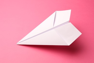 Photo of Handmade white paper plane on pink background