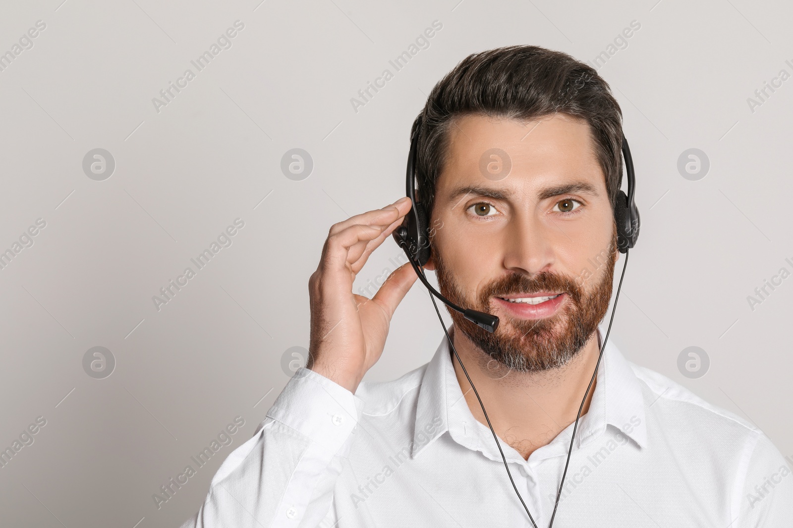 Photo of Hotline operator with headset on light grey background, space for text