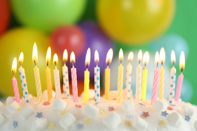 Photo of Birthday cake with burning candles against blurred background, closeup