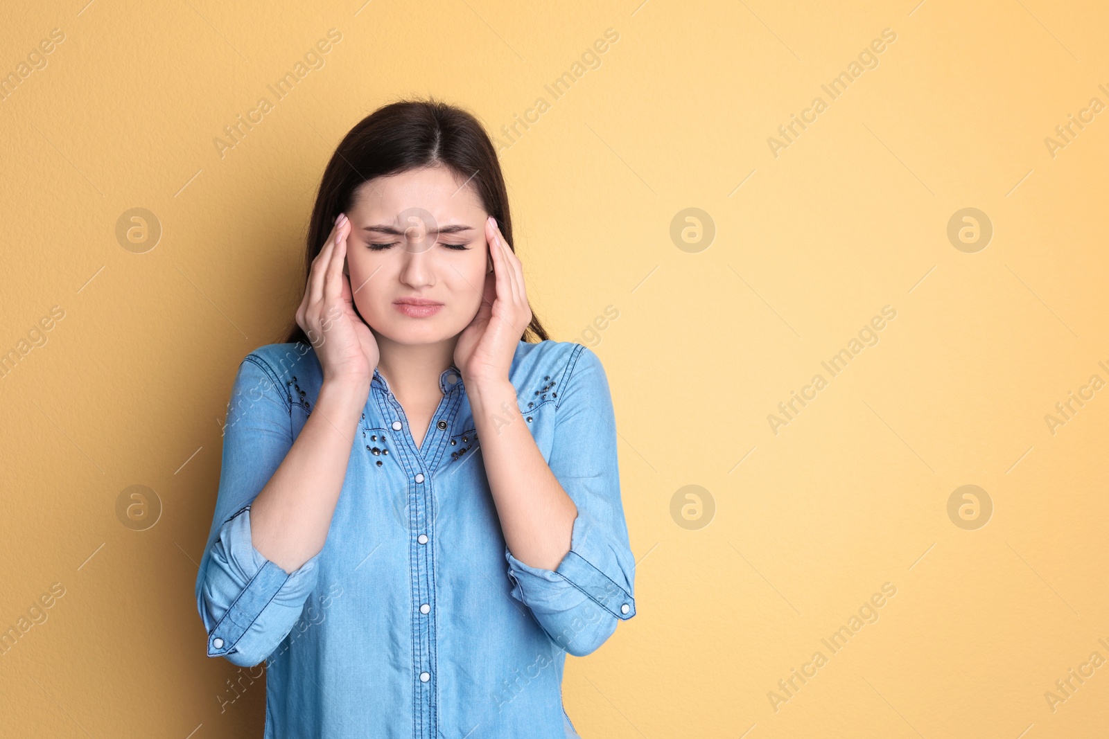 Photo of Young woman suffering from headache on color background