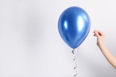 Photo of Woman piercing balloon with needle on white background, closeup