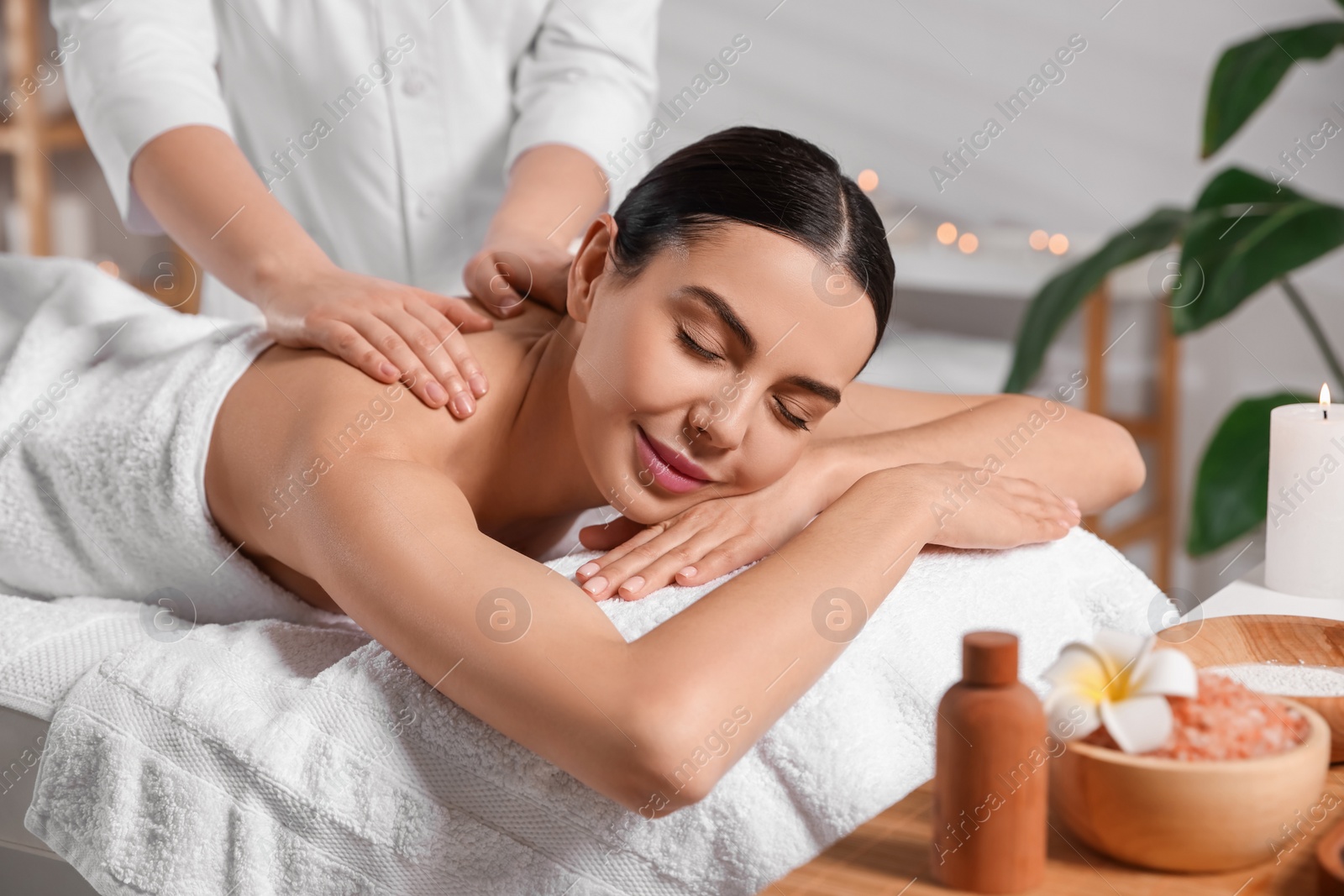 Photo of Beautiful woman receiving back massage in beauty salon, closeup