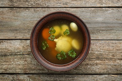 Delicious chicken bouillon with parsley, carrot and eggs on wooden table, top view
