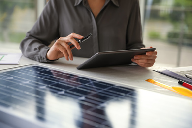 Photo of Woman working on  project with solar panels at table in office, closeup