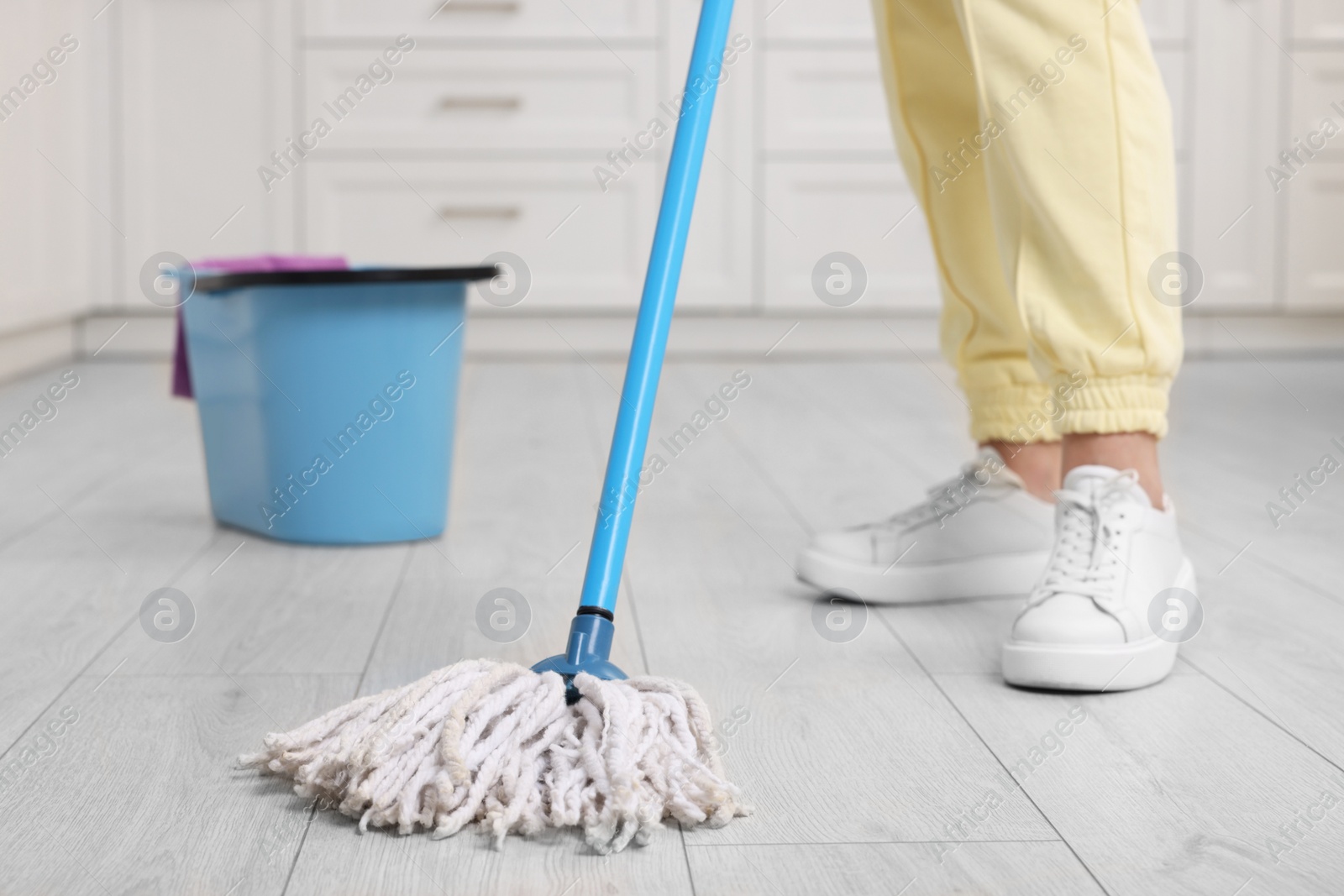 Photo of Woman cleaning floor with mop indoors, selective focus