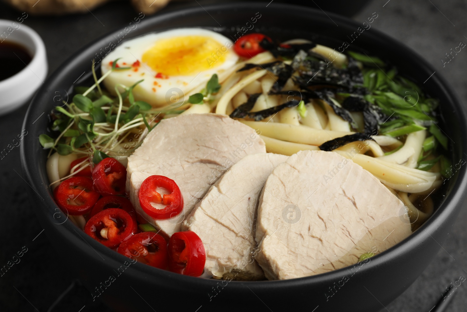 Photo of Delicious ramen with meat in bowl on grey table, closeup. Noodle soup