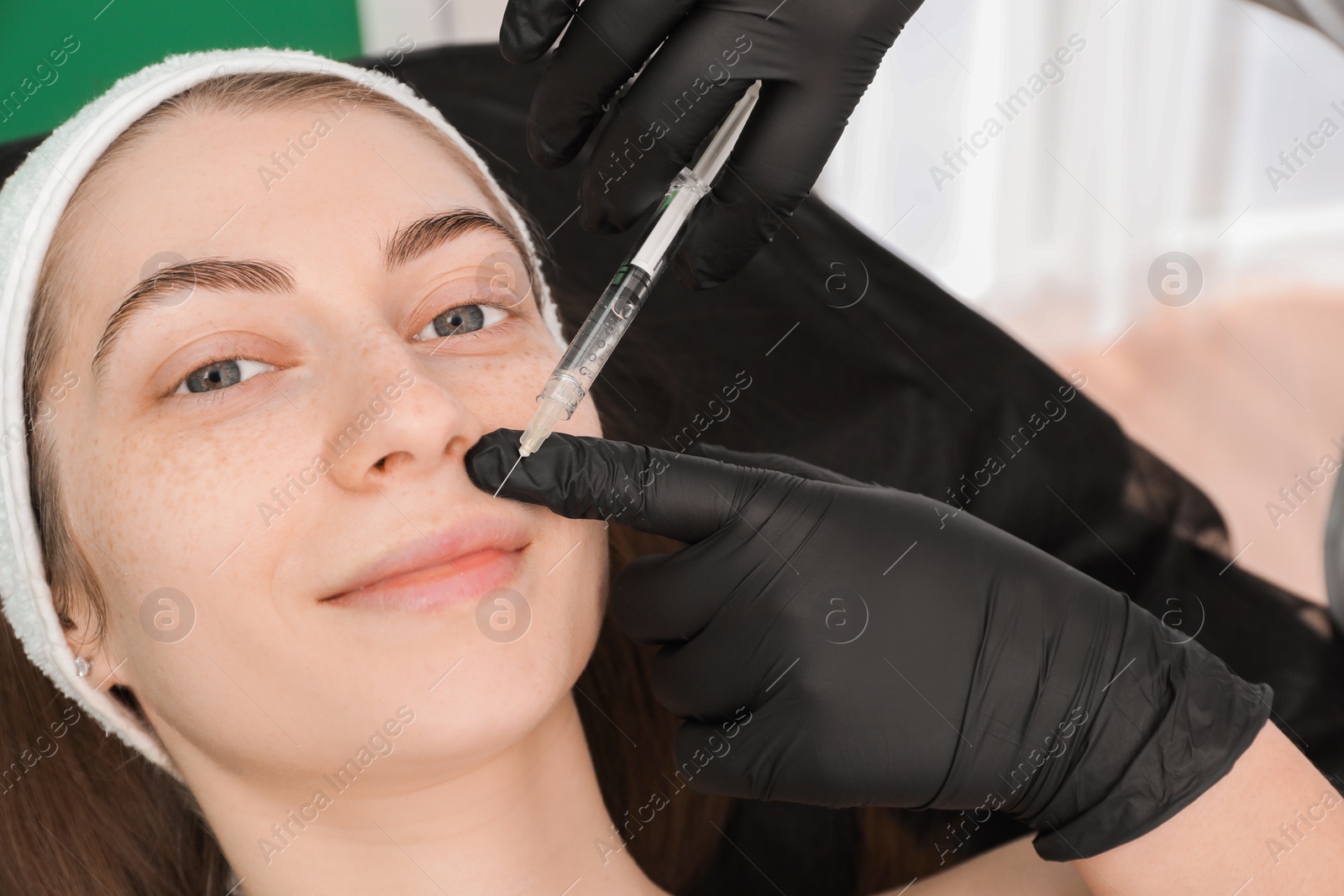 Photo of Cosmetologist giving lips injection to patient indoors, closeup. Cosmetic surgery