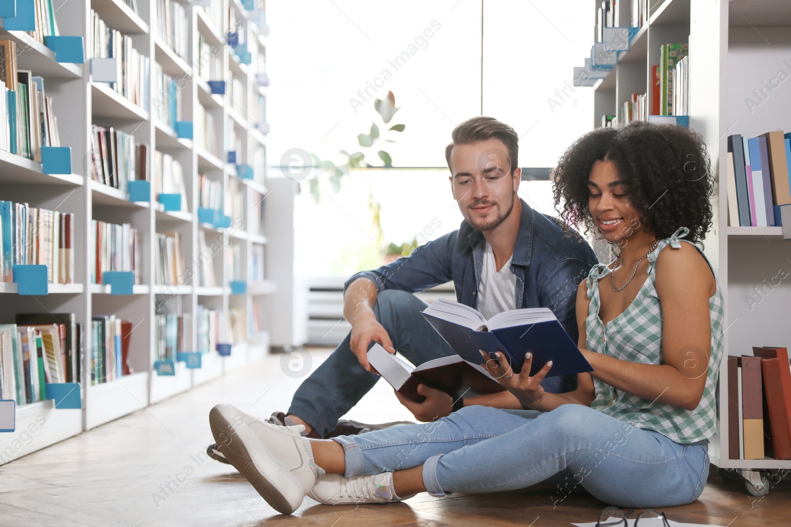 Photo of Young people with books on floor in library