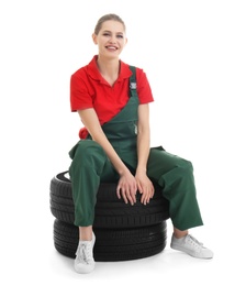 Female mechanic with car tires on white background