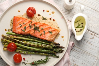 Photo of Tasty grilled salmon with tomatoes, asparagus and spices on table, flat lay