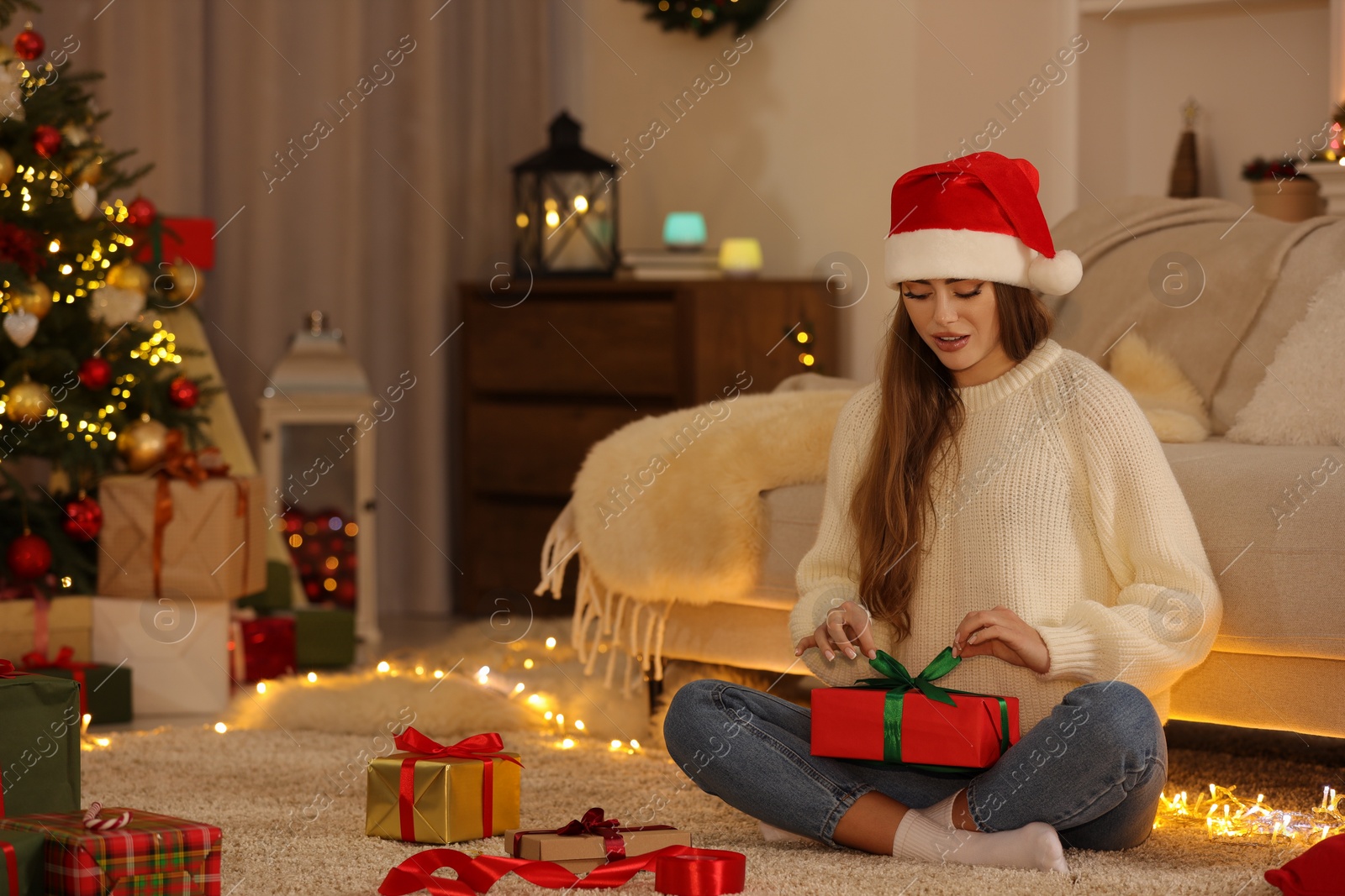 Photo of Beautiful young woman decorating Christmas gift at home