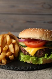 Photo of Delicious burger and french fries served on grey table, closeup