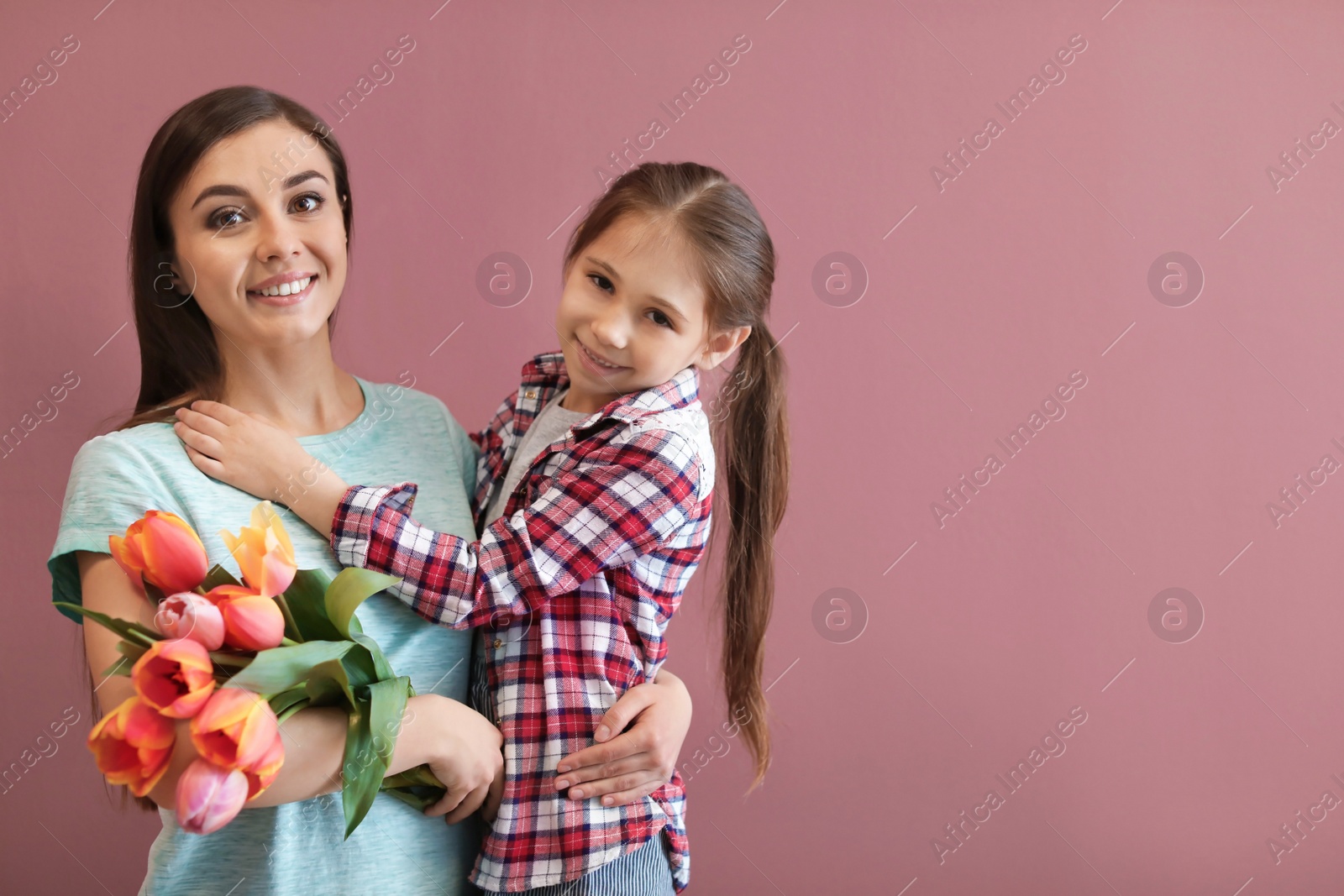 Photo of Portrait of happy woman with flowers and her daughter on color background. Mother's day celebration