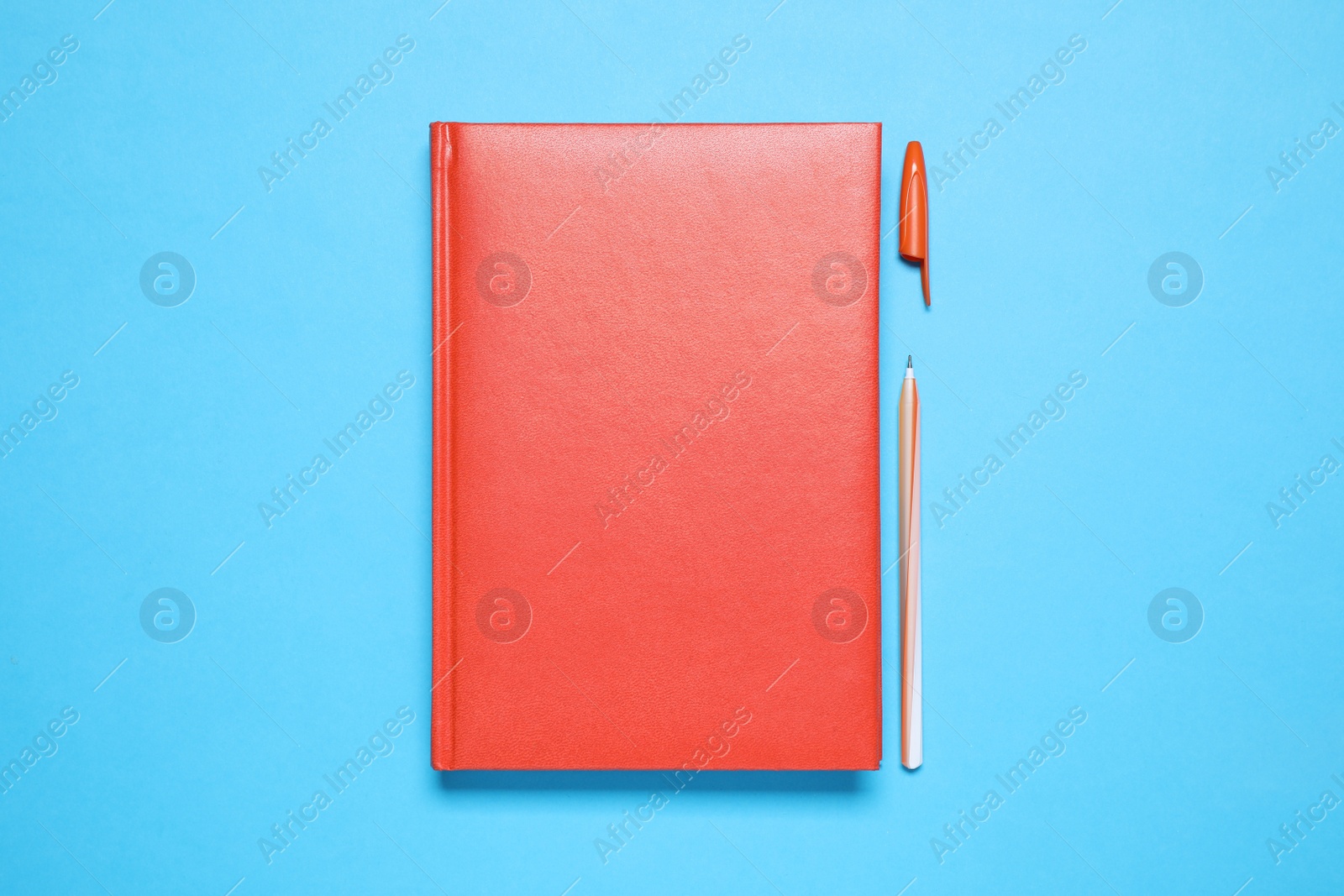 Photo of Stylish red notebook and pen on light blue background, flat lay