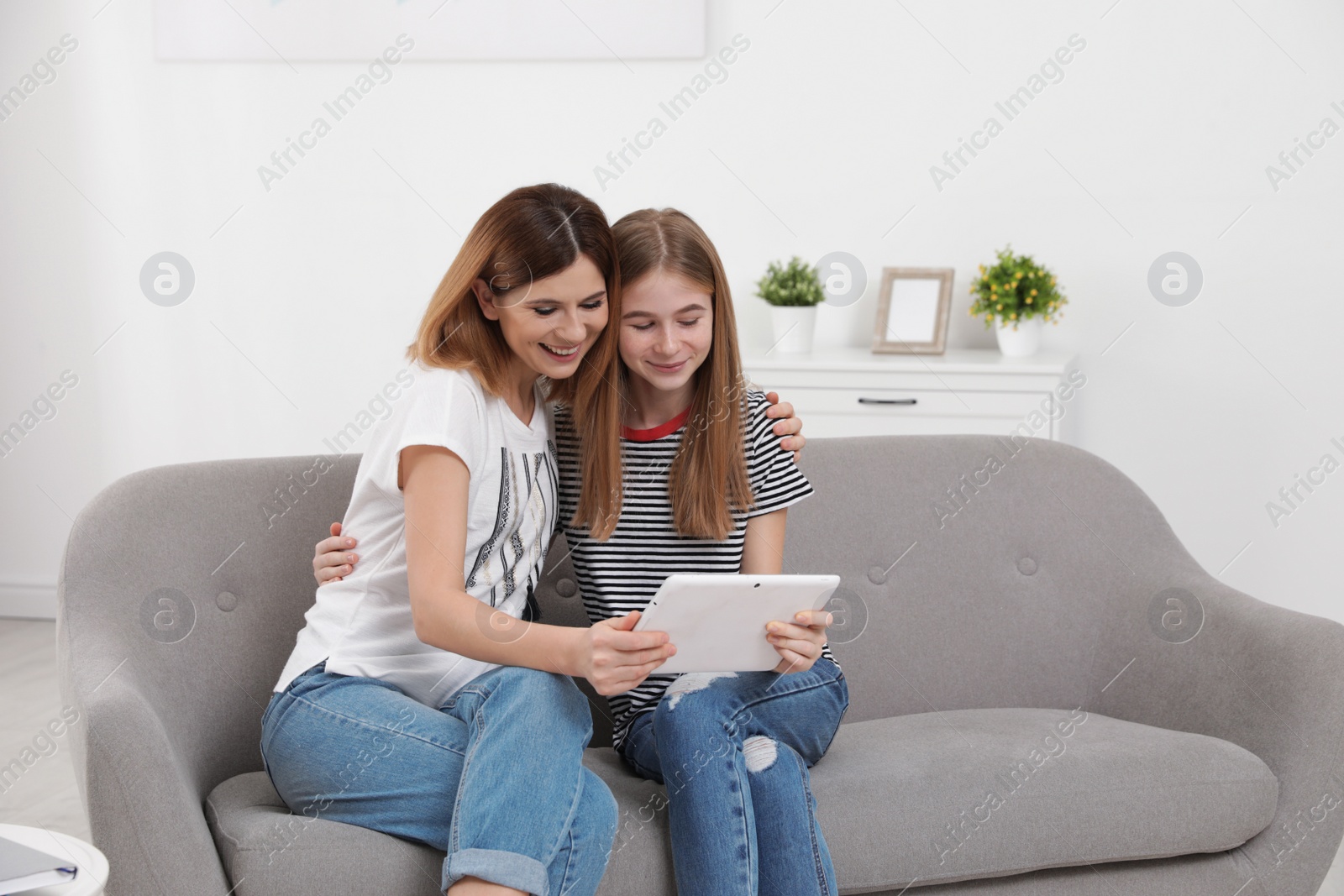 Photo of Happy mother and her teenager daughter with tablet computer at home