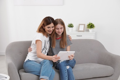 Happy mother and her teenager daughter with tablet computer at home