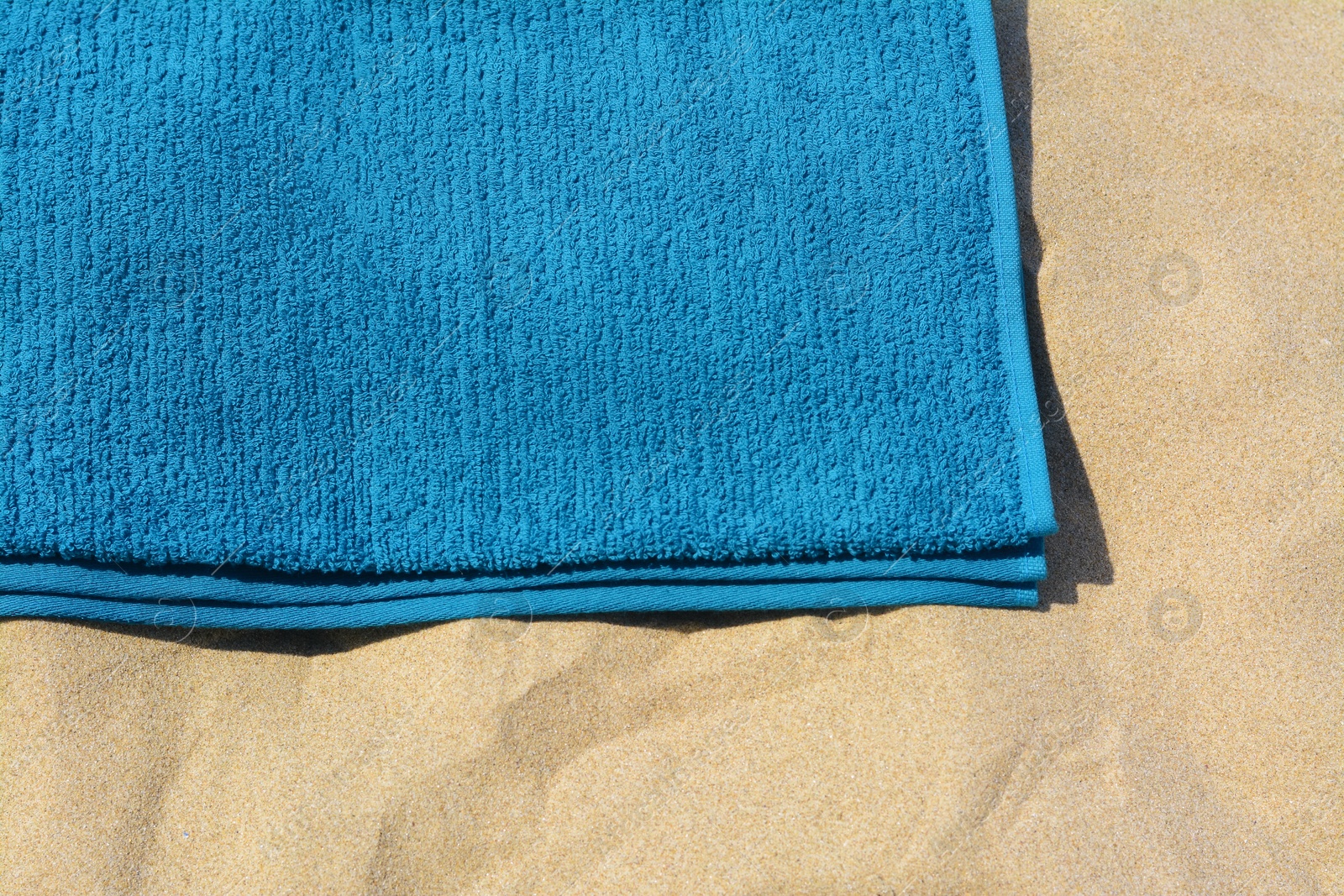 Photo of Soft blue beach towel on sand, above view