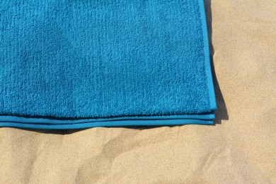 Photo of Soft blue beach towel on sand, above view