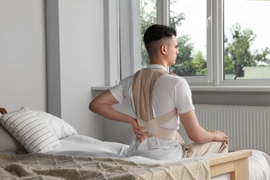 Man with orthopedic corset sitting in bedroom