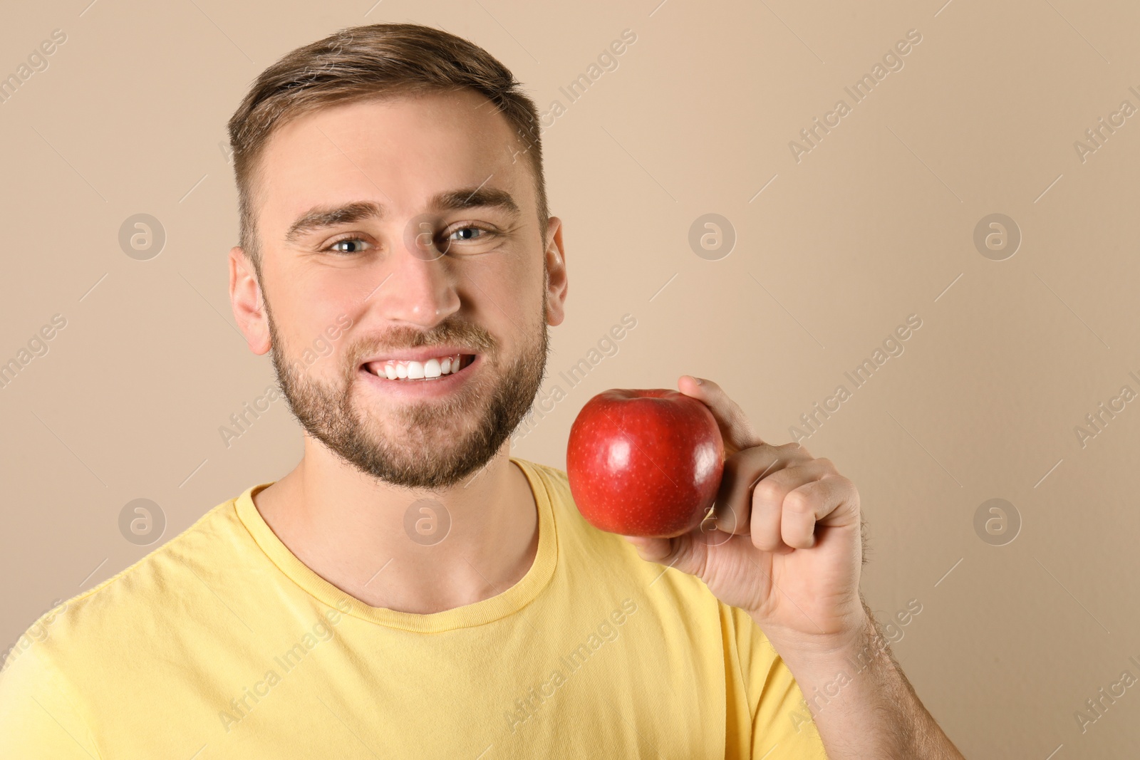 Photo of Young man with healthy teeth and apple on color background. Space for text