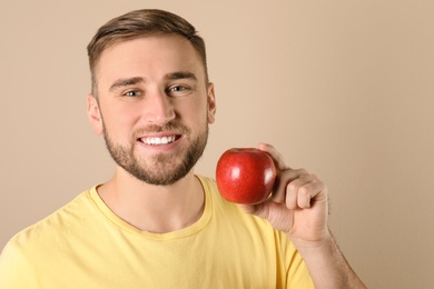 Photo of Young man with healthy teeth and apple on color background. Space for text