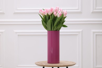 Beautiful bouquet of fresh pink tulips on table near white wall