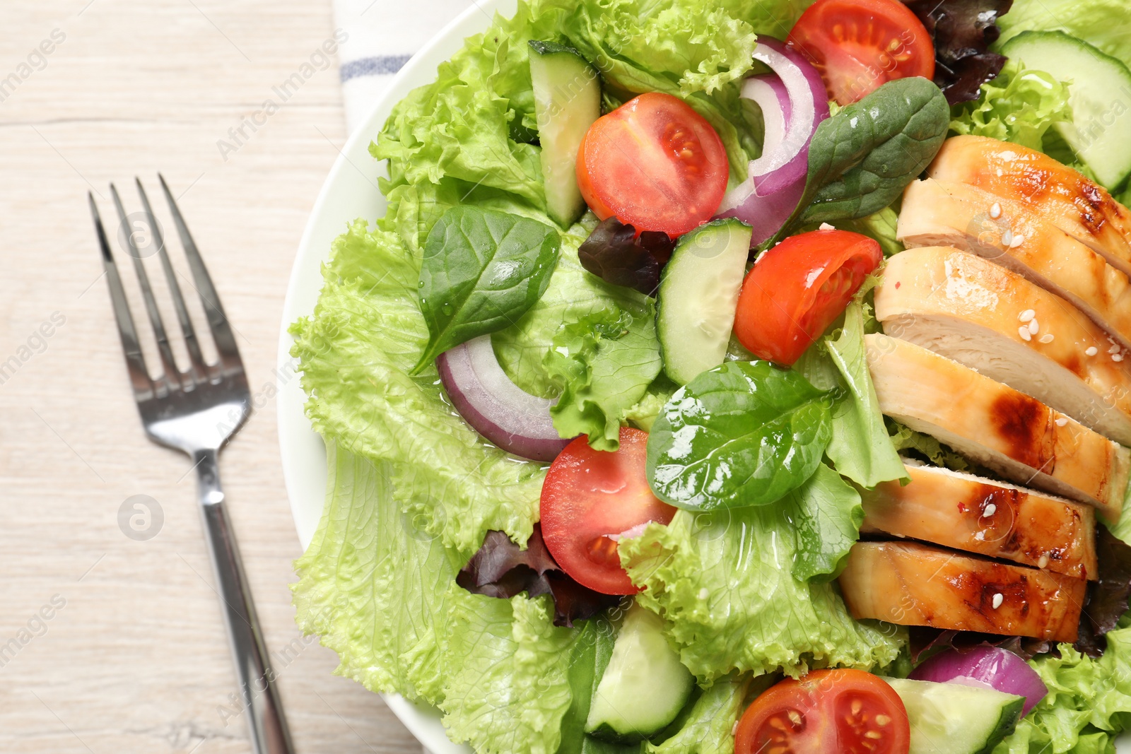 Photo of Delicious salad with chicken, vegetables and fork on wooden table, top view