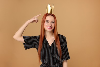 Beautiful young woman with princess crown in dress on beige background