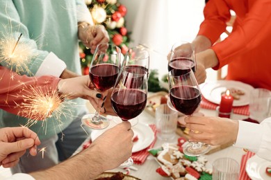 Photo of Family with their friends clinking glasses at festive dinner indoors, closeup. Christmas Eve celebration