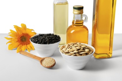 Photo of Bottles of different cooking oils, sunflower and seeds on white background