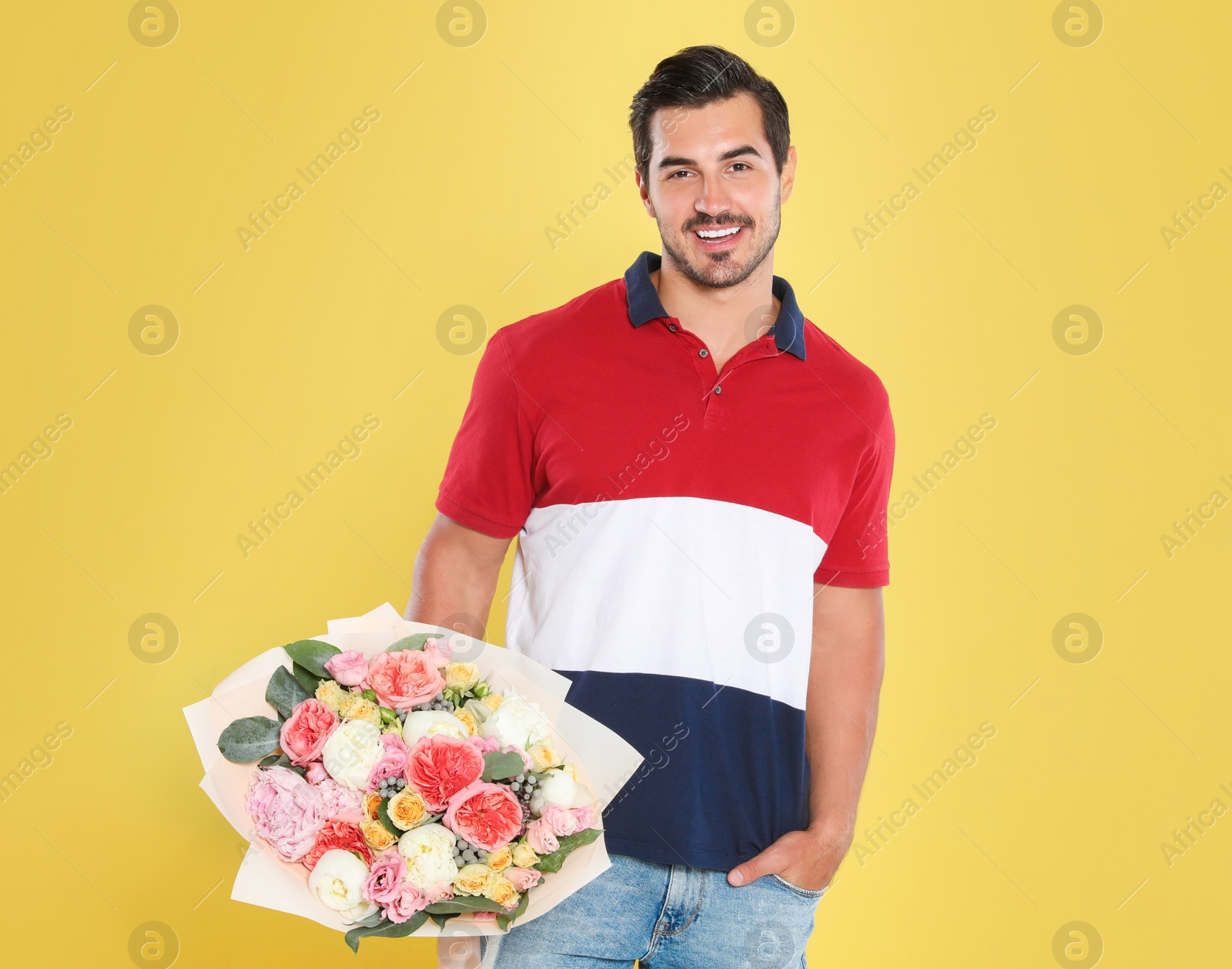 Photo of Young handsome man with beautiful flower bouquet on yellow background