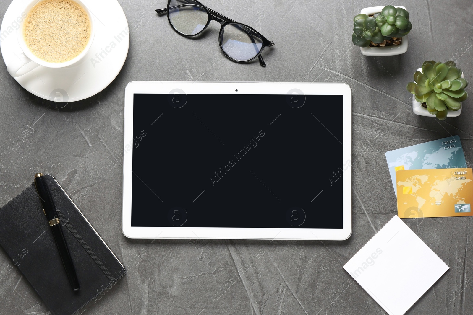 Photo of Online store. Tablet, stationery, glasses, credit cards, coffee and houseplants on grey table, flat lay