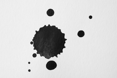 Photo of Blots of black ink on white background, flat lay