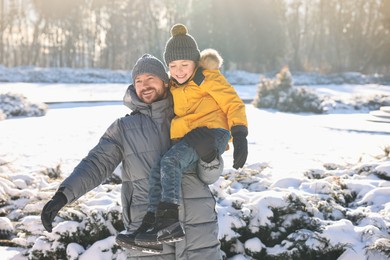 Family portrait of happy father and his son in sunny snowy park