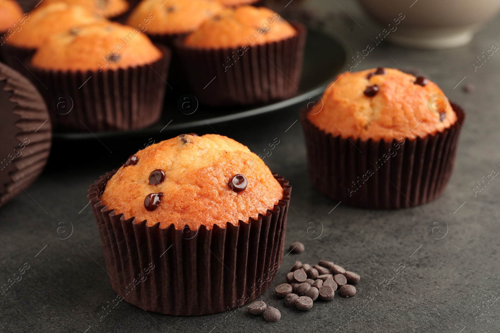 Photo of Delicious freshly baked muffins with chocolate chips on gray table, closeup